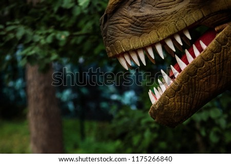 Jaws of a mechatronic dinosaur with sharp teeth in forest