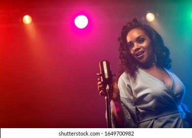 A jazz singer performs on stage. Afro.