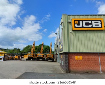 JCB company logo seen on the building and it's branded equipment at the background. Stoke on Trent, United Kingdom - June 12, 2022. 