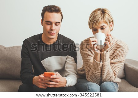 Jealous girl spying her boyfriend's mobile phone while he typing a message