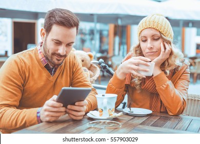Jealous girlfriend.Young woman looks suspicious while her boyfriend is texting on smart phone.