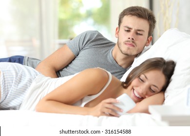 Jealous gossip husband watching his wife mobile phone on the bed at home
