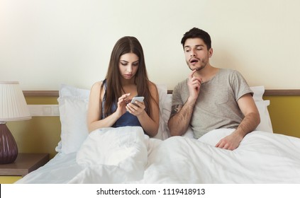 Jealous husband watching his wife mobile phone while woman texting on the bed at home