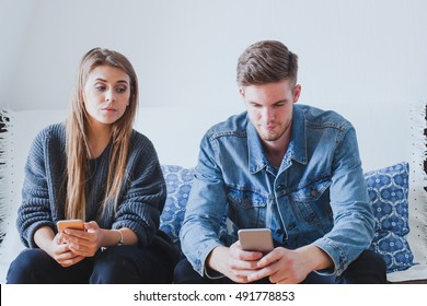 jealous wife spying husband, suspicious girlfriend trying to read messages on the mobile phone of her boyfriend while he is not watching