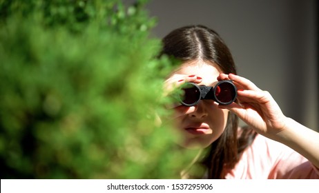 Jealous woman with binoculars hiding behind tree spying for husband, betrayal