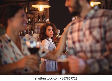 Jealous woman looking at couple flirting with each other in pub