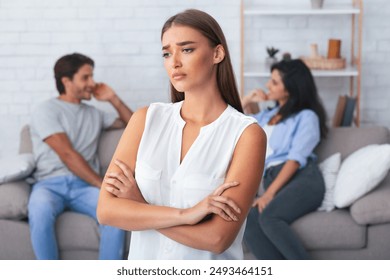 Jealousy Concept. Offended Girlfriend Standing Crossing Hands While Her Boyfriend Flirting With Girl Sitting On Sofa Indoor. Shallow Depth - Powered by Shutterstock