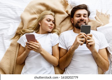 Jealousy.Young Couple Use Smatphones. Tecnology Concept