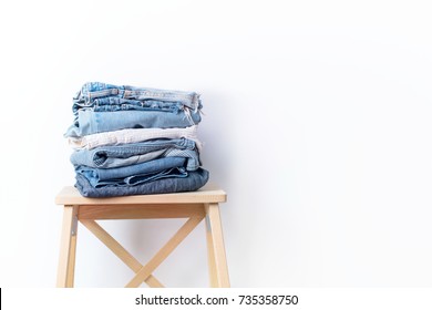 Jeans Denim Cloth Garment Monochrome Gray Blue Linen Textile Stacked On Wooden Chair Near White Wall Pile Concept