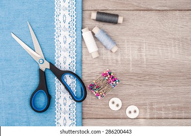 Jeans fabric for sewing, lace and accessories for needlework on old wooden background. Spool of thread, scissors, buttons, sewing supplies. Set for needlework top view - Powered by Shutterstock