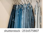 Jeans hanging on hooks organized in closet