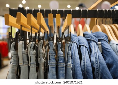 Jeans on the hanger in the store. Clothes on hangers in shop for sale. Blur background. Fashionable clothes in a boutique. Various clothing on market. Shopping in store. - Powered by Shutterstock