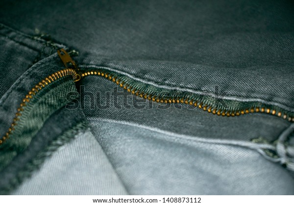 Jeans with open fly, zipper\
divides the picture into different zones. There is a round\
frame-lamp.