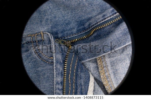 Jeans with open fly, zipper
divides the picture into different zones. There is a round
frame-lamp.