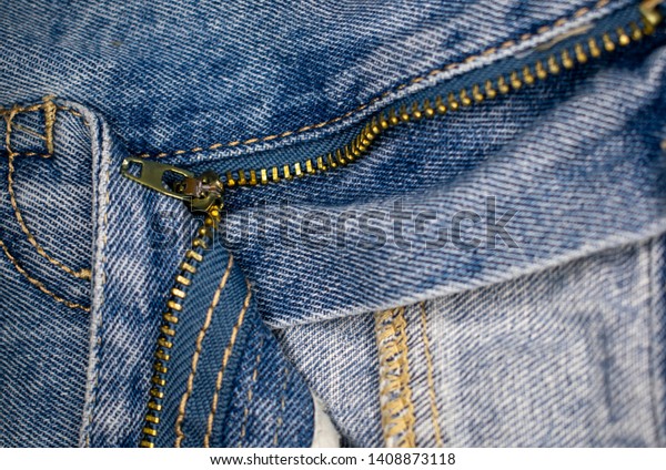 Jeans with open fly, zipper\
divides the picture into different zones. There is a round\
frame-lamp.