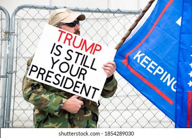 JEFFERSON CITY, MO - November 14, 2020: Man in camo holds a "Trump is Still Your President" sign during a "Stop the Steal" rally, echoing unfounded allegations of voter fraud in the US election.