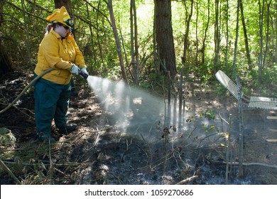 Jefferson, Oregon/ USA - 05-17-2009  Female Fire Fighter Spraying Water On The Burnt Area