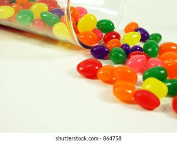 Jelly Beans Falling Out Of A Glass Jar Isolated On White.