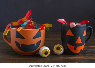 Gusanos de dulces gelatinosos, taza de Halloween sobre fondo oscuro. Decoración y dulces de Halloween.