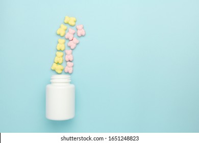 Jelly Teddy Bear Vitamin Gummies Sprinkled From The Bottle On A Blue Background. Advertisement Concept Of Medicine For Children