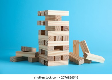 Jenga tower made of wooden blocks on light blue background
