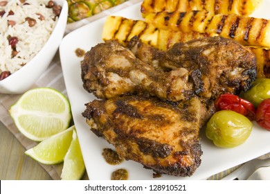 Jerk Chicken - Jamaican marinated BBQ chicken served with grilled pineapple, rice and peas and lime wedges.