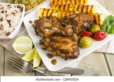 Jerk Chicken - Jamaican Marinated BBQ Chicken Served With Grilled Pineapple, Rice And Peas And Lime Wedges.