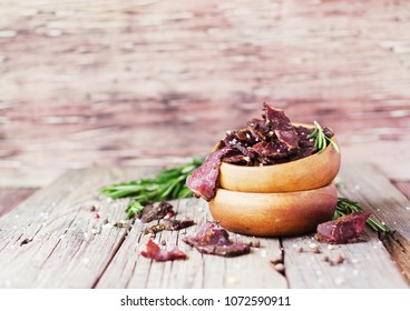 jerked dried meat, cow, deer, wild beast or biltong in wooden bowls on a rustic table, selective focus