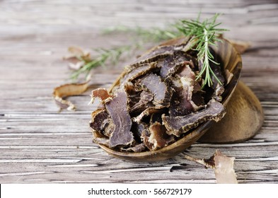 jerked meat, cow, deer, wild beast or biltong in wooden bowls on a rustic table, selective focus