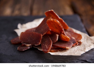 Jerky With Spices On A Black Stone Cutting Board, Dark Background. Beer Snack.