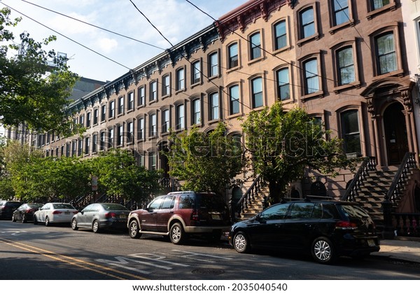 Jersey City, New Jersey USA - May 4 2021: Long Row\
of Colorful Old Brownstone Homes in Jersey City New Jersey along a\
Neighborhood Street