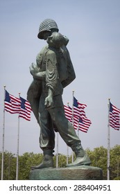 JERSEY CITY, NJ - MAY 26 2015: The Liberation Monument, a Holocaust memorial depicting a US soldier carrying a Nazi death camp survivor, with American Flags in the US Flag Plaza in Liberty State Park. - Shutterstock ID 288404951