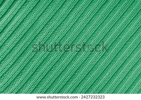 Jersey textile background , green diagonal striped knitted fabric. Woolen knitwear, sweater, pullover surface texture, textile structure, cloth surface, weaving of knitwear material