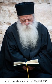 JERUSALEM - APRIL 22: An Orthodox Christian Priest With A Long White Beard Sits Reading His Bible Outside The Church Of The Holy Sepulcher In Jerusalem On Good Friday, April 22, 2011.