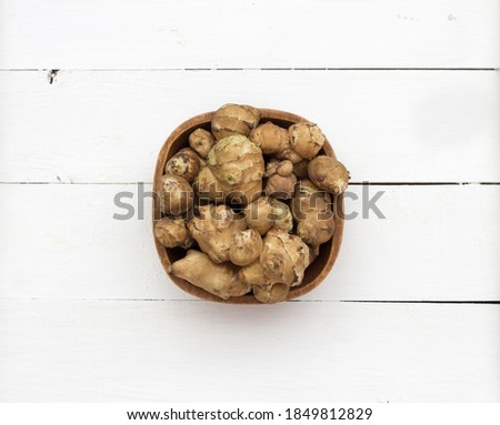 Jerusalem artichoke in a brown wooden bowl on a white colored wooden background, close up, table, top view [[stock_photo]] © 