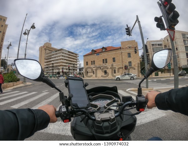 Jerusalem, Israel - April\
16, 2019: Riding a scooter in the busy urban streets during a\
cloudy and sunny\
day.