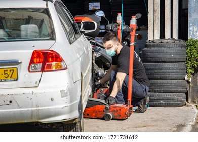 Jerusalem, Israel - April 21st, 2020: A Worker At A Tire Repair Shop Fully Protected Against COVID19 With Gloves And A Mask.