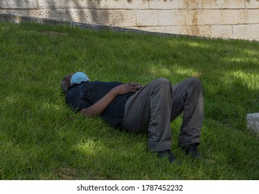 Jerusalem, Israel - July 30th, 2020: A Man Having A Mid Day Power Nap, Wearing A COVID Mask In A Jerusalem, Israel, Park.