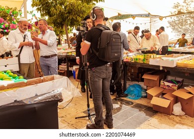 JERUSALEM, ISRAEL - SEPTEMBER 20, 2018: Sukkot Is A Jewish Holiday. TV Reporter Recording An Interesting Scene. Pre-holiday Bazaar For The Sale Of Ritual Plants. 