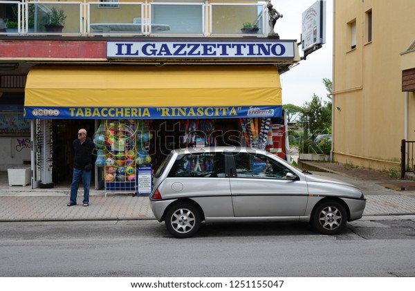 JESOLO, ITALY - JUNE 28,\
2013: Lancia Y (Ypsilon) popular Italian 1990s compact on the city\
road in front of newspaper shop IL GAZETINO. Typical Italian street\
view.