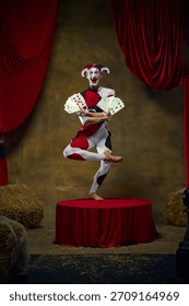 Jester balancing multiple retro card fans in dynamic stage pose. Concept of casino-show advertising, themed posters, energetic performance branding, and expressive entertainment content.