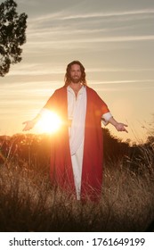 Jesus Christ backlit in sunlight with hands outstretched in blessing and clothed in his traditional red and white robe