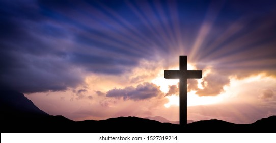 Jesus Christ cross on an amazing mountain sunset background with dramatic lighting and sunbeams. Easter, resurrection concept. Christian wooden cross