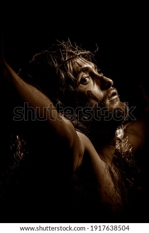 Jesus Christ crucified with crown of thorns during the passion. Sepia tones.