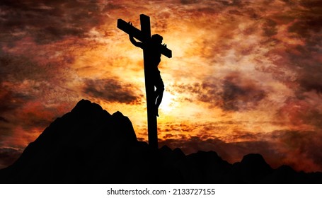 Jesus Christ crucified on the cross at Calvary hill with burning sky in background - Shutterstock ID 2133727155
