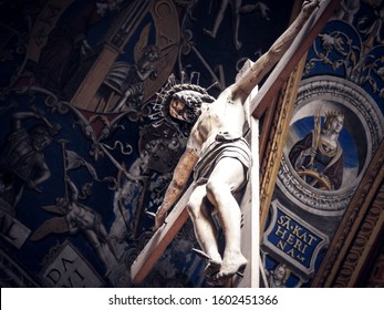 Jesus Christ nailed on a large wooden crucifix at Albi Cathedral with Renaissance frescoes of church ceiling in the background. Religious statue, Tarn department of Occitanie, France