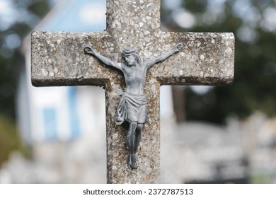 Jesus crucified metal statue. Weathered concrete cross. Graveyard background. Rusty grunge symbol. All saints day. Old abandoned tombstone. Cemetery grave. Catholic religion symbol.