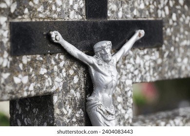 Jesus crucified metal statue. Weathered concrete cross. Graveyard background. Rusty grunge symbol. All saints day. Old abandoned tombstone. Cemetery grave. Catholic religion symbol.