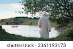 Jesus meditate by the river Jordan with a fishing boat in background.