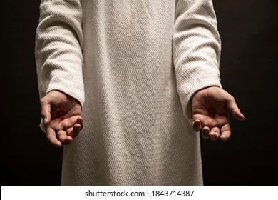 Jesus of Nazareth showing the wounds on his hands while praying on a dark night after being resurrected.